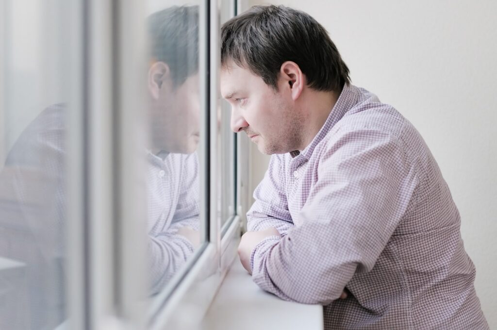 Individual sitting by a window, deep in thought, symbolizing reflection on PTSD experiences