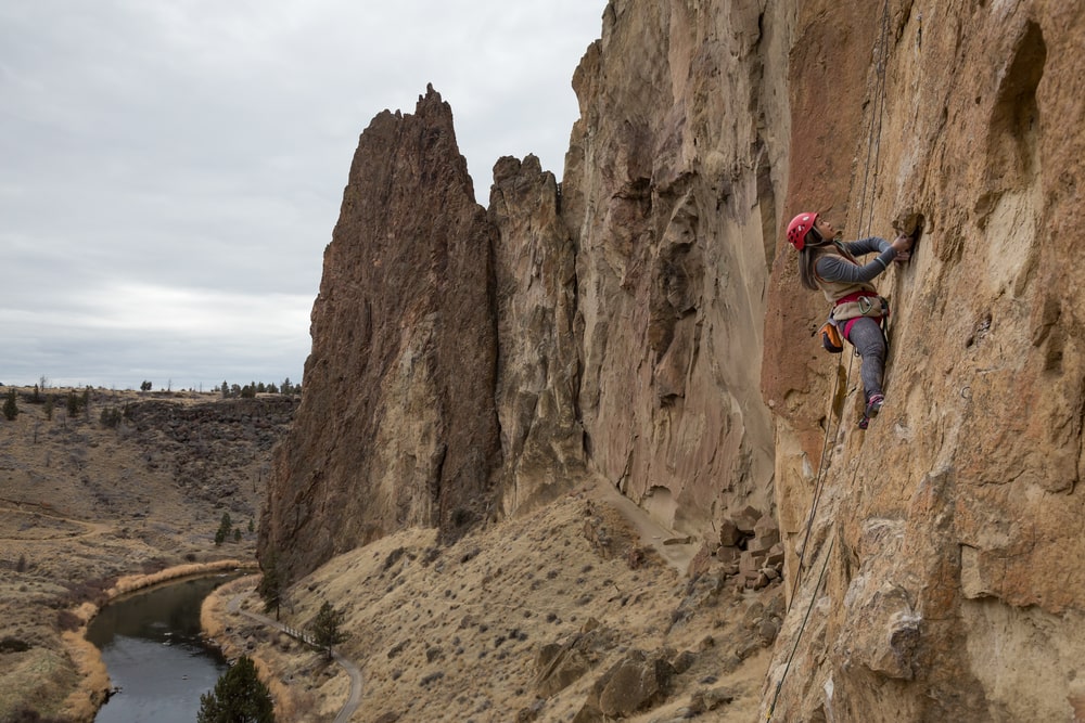 Climber scaling a natural rock formation, showcasing determination and strength-min