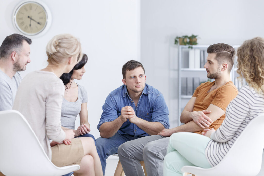 Focused man talking to people in a group therapy for addiction